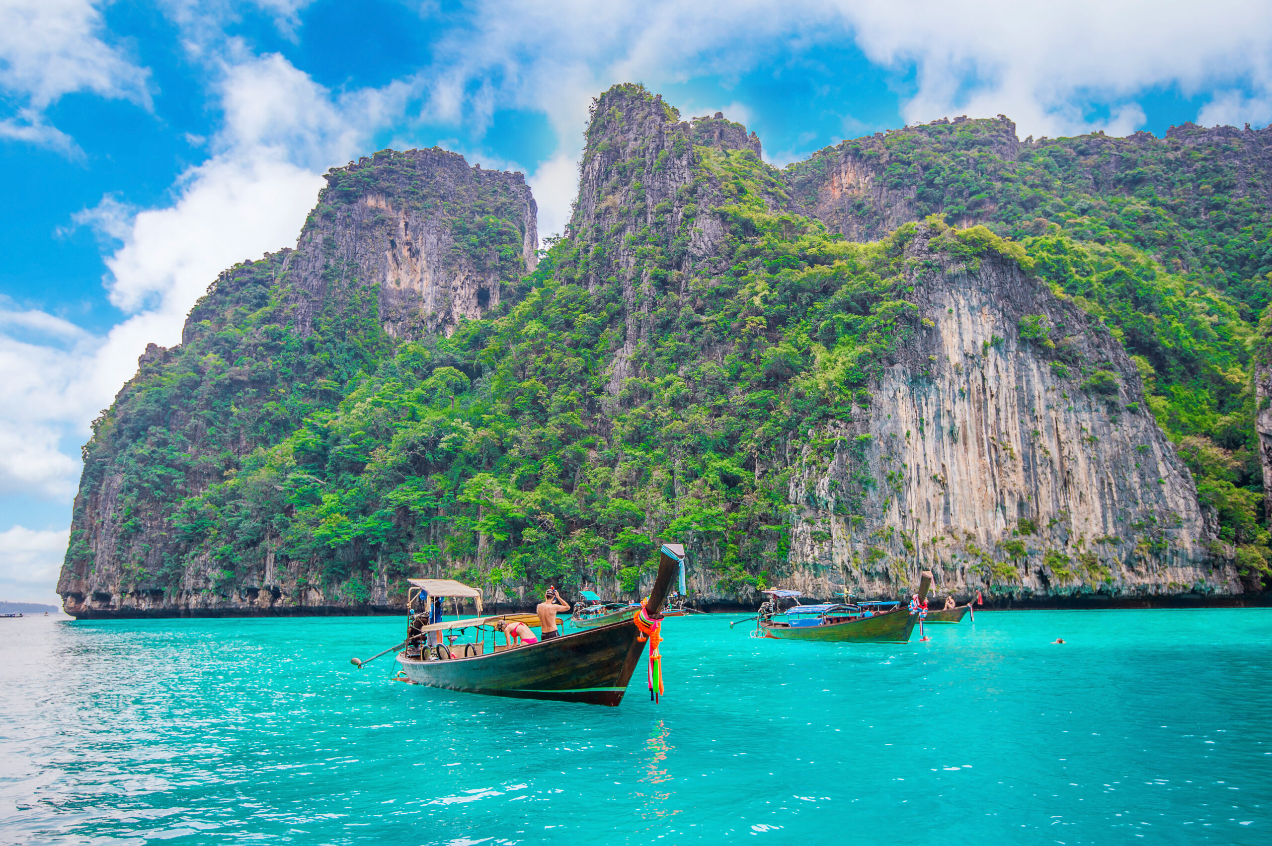 A beautiful beach in Thailand with crystal clear turquoise water, palm trees, and white sand.