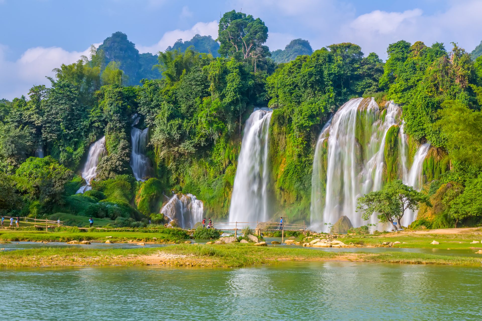 A stunning waterfall cascading down rocky cliffs in Vietnam, surrounded by lush greenery and misty air.jpeg